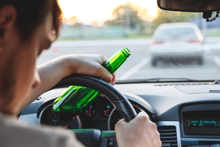 man driving while drinking alcohol